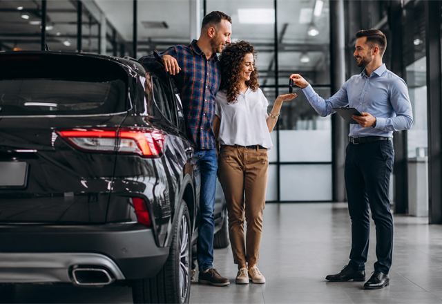 Vendedor entregando a chave de um carro na concessionária